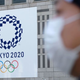 A man wearing a face mask walks by a sign announcing the Tokyo Olympics in March 2020.